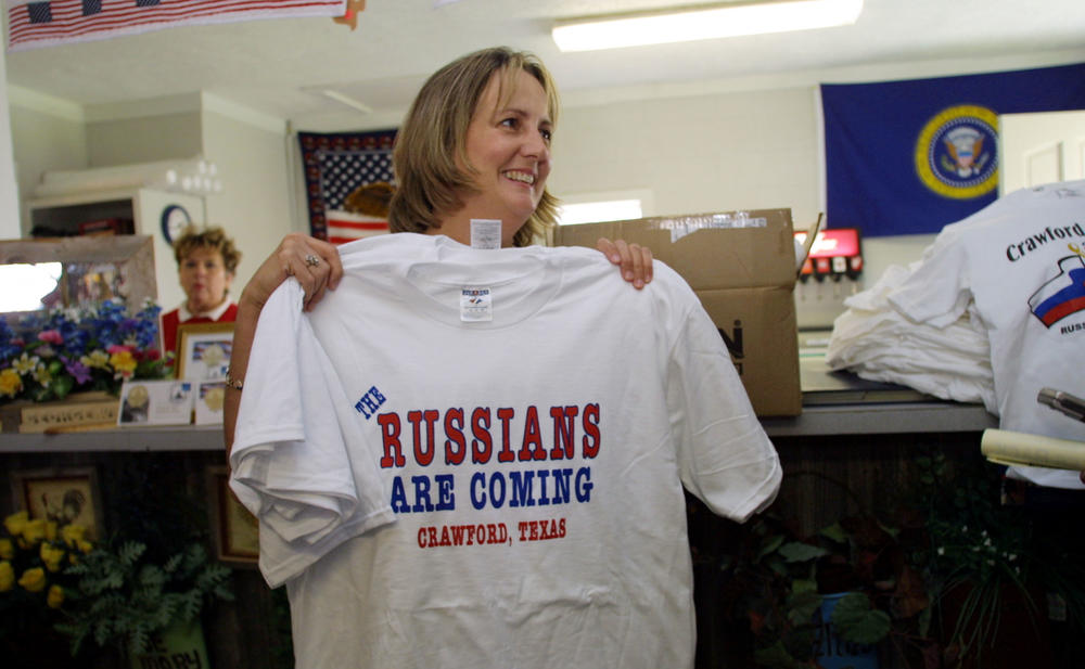 A woman holds up a T-shirt that says 