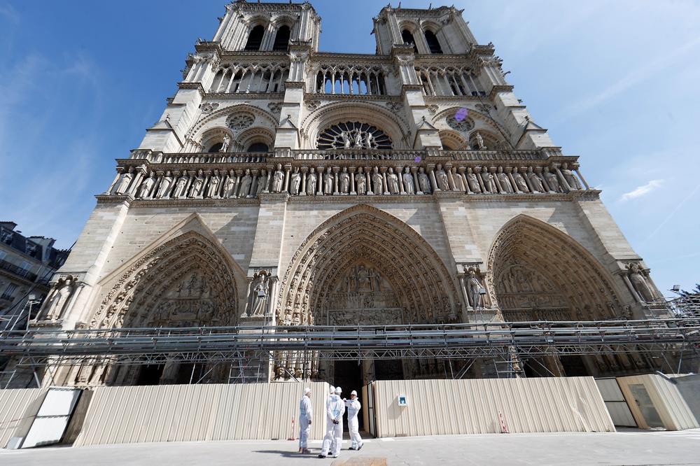 Workers stand outside the reconstruction site at the Notre Dame Cathedral in Paris on Friday.