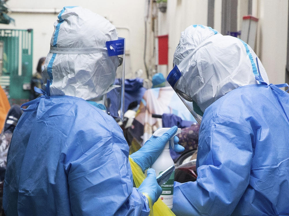 In this photo released by China's Xinhua News Agency, a medical worker disinfects another after taking samples for COVID-19 tests in a residential area in Shanghai, China, Saturday, April 16.