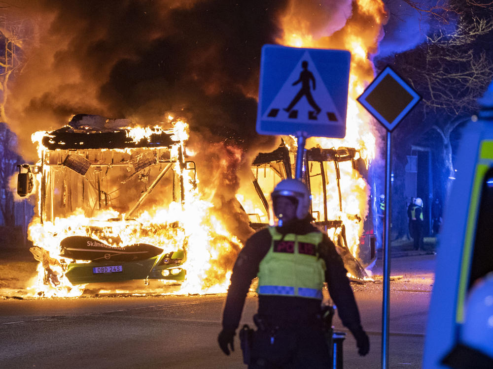 Riot police watch a city bus burn on a street in Malmo, Sweden, on Saturday. Unrest broke out in southern Sweden late Saturday despite police moving a rally by an anti-Islam far-right group, which was planning to burn a Quran among other things, to a new location as a preventive measure.
