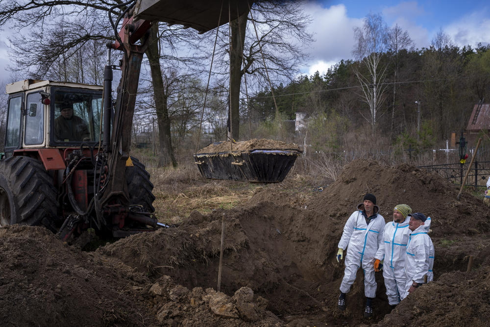 <strong>April 17:</strong> A crane lifts a casket as volunteers remove the soil from a mass grave during an exhumation of four civilians killed in Mykulychi, Ukraine. All four bodies in the village grave were killed on the same street, on the same day. Their temporary caskets were together in a grave.