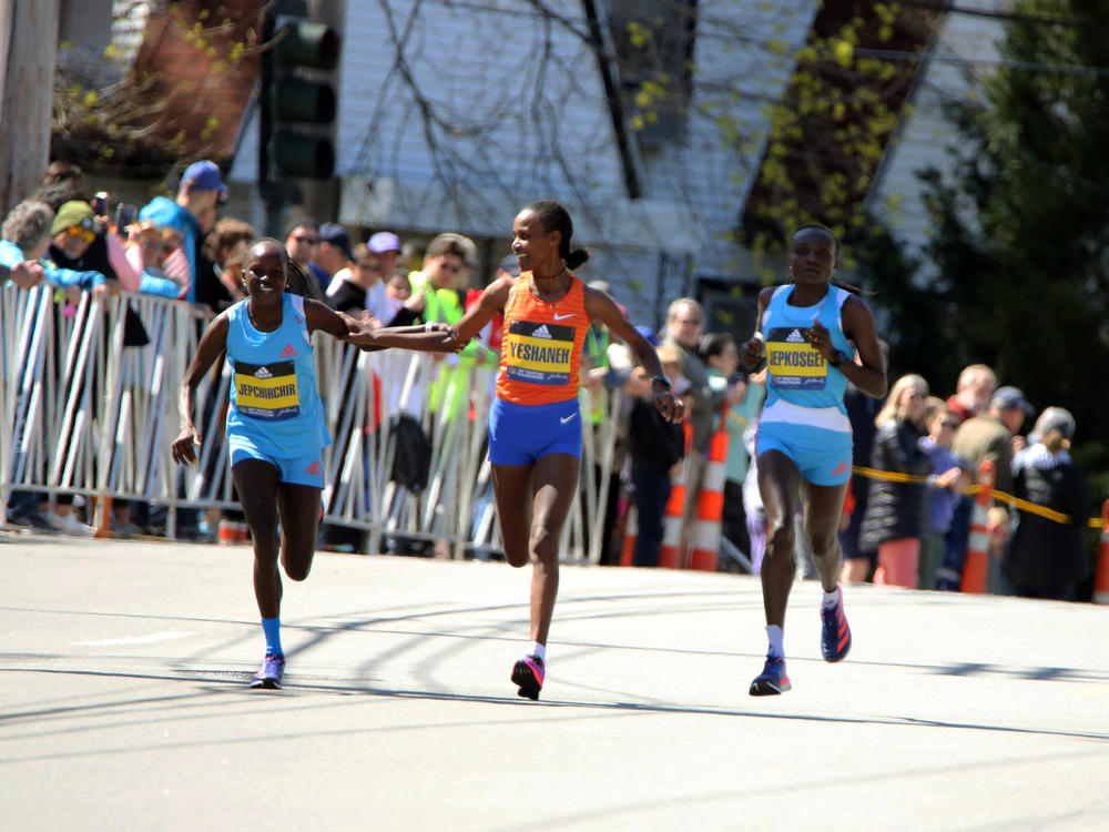 Peres Jepchirchir, of Kenya, left, and Ababel Yeshaneh, of Ethiopia, clasp each other's arms during the Boston Marathon on Monday. Jepchirchir won the women's division and Yeshaneh finished second. At right is Joyciline Jeopkosgei, of Kenya.