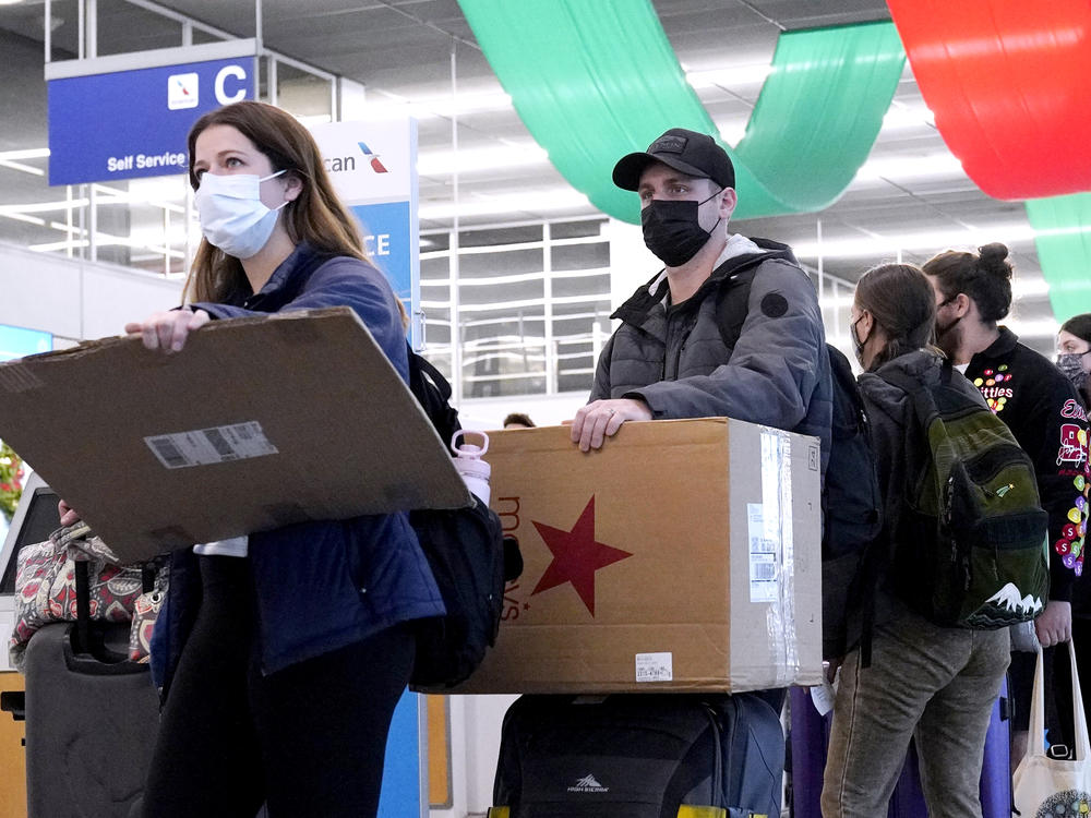 Travelers line up wearing protective masks indoors at O'Hare International Airport in Chicago in December 2021. U.S. District Judge Kathryn Kimball Mizelle voided the national travel mask mandate on Monday.