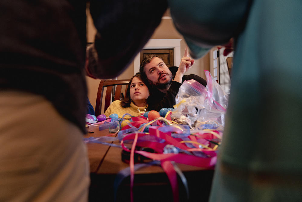Artem Koliubaiev and younger daughter Amira listen to their host, Susan Thompson-Gaines, while stuffing Easter eggs with snacks and candies on April 9.