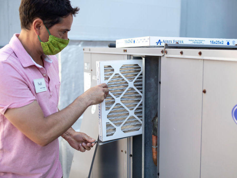 Mark Marston slides a higher-quality air filter back into an upgraded HVAC system in Portland, Maine. The new system can bring in about 30% more outside air.