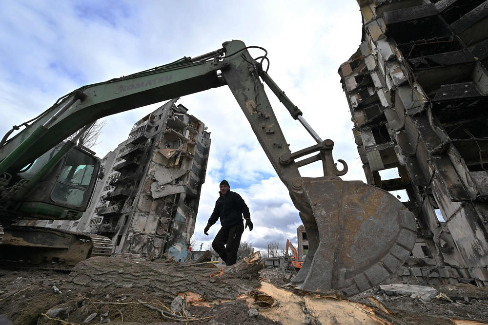 <strong>April 17:</strong> A digger and a communal worker clean debris off buildings destroyed in Russian bombardments in the Ukrainian town of Borodianka, in the Kyiv Oblast.