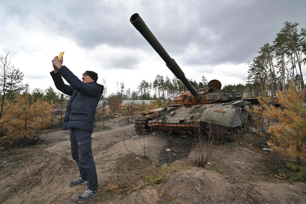 <strong>April 17:</strong> A man takes a selfie as he stands in front of a ruined Russian tank in the village of Andriivka, in the Kyiv oblast.