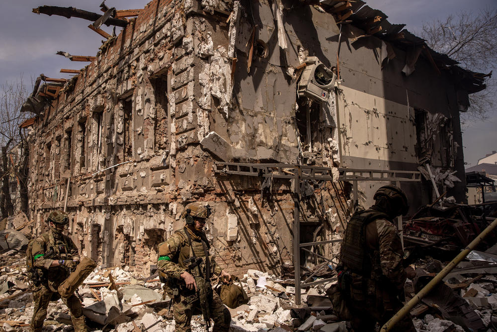 <strong>April 16:</strong> Members of the Ukrainian military walk amid debris after a shopping center and surrounding buildings were hit by a Russian missile strike in Kharkiv, in eastern Ukraine. After Russian forces retreated from areas around Kyiv, officials say they anticipate a new offensive in the eastern part of the country.