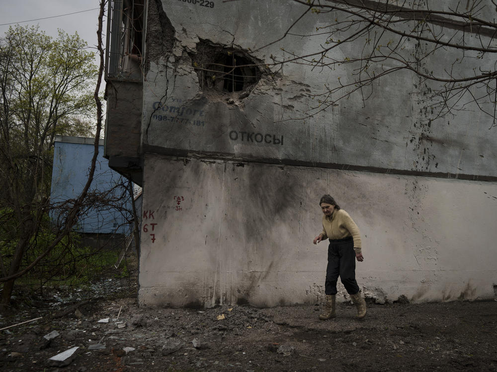 A woman walks next to a damaged building after a Russian bombardment in Kharkiv, Ukraine, on Tuesday. Russia ratcheted up its battle for control of Ukraine's eastern industrial heartland on Tuesday, intensifying assaults on cities and towns along a front hundreds of miles long in what officials on both sides described as a new phase of the war.