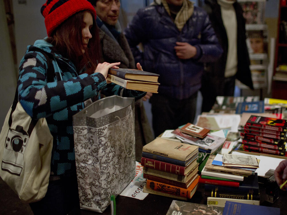 In this photo taken on Thursday, Feb. 6, 2014, a woman delivers some of her books as part of her contribution to fill the shelves of an improvised library set inside the Ukrainian House in Kiev.