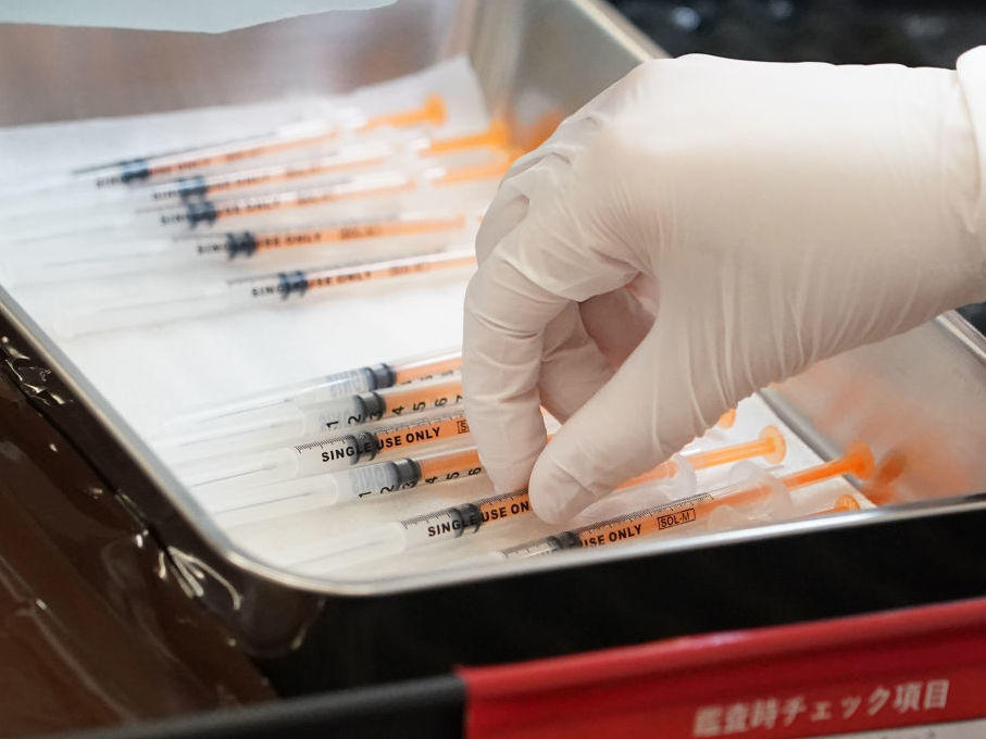 A health care worker prepares the current COVID vaccine booster shots from Moderna in February. The company says a bivalent vaccine that combines the original strain with the omicron strain is the lead candidate for a fall vaccination campaign.