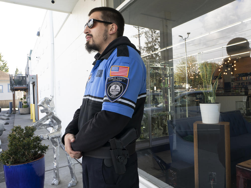 Security guard Austin MacMath wears a gun on his belt while working outside Mary Mart, a marijuana store in Tacoma, Wash., on Tuesday.