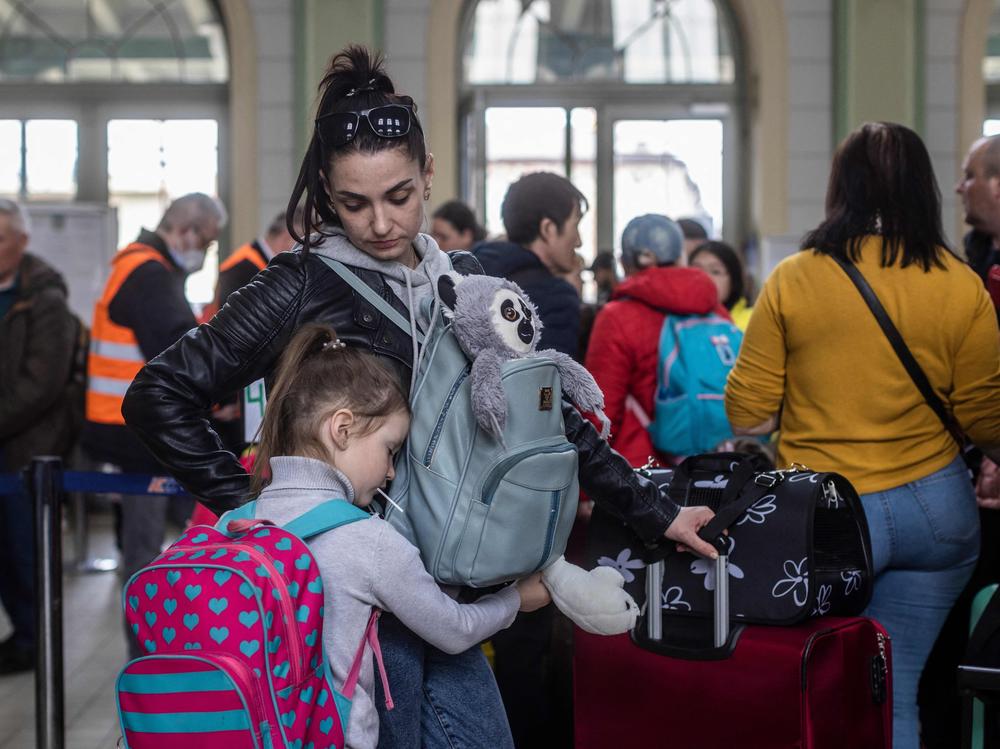 A woman and a child, along with other refugees from Ukraine, wait in the ticket hall of the railway station in Przemysl in eastern Poland.