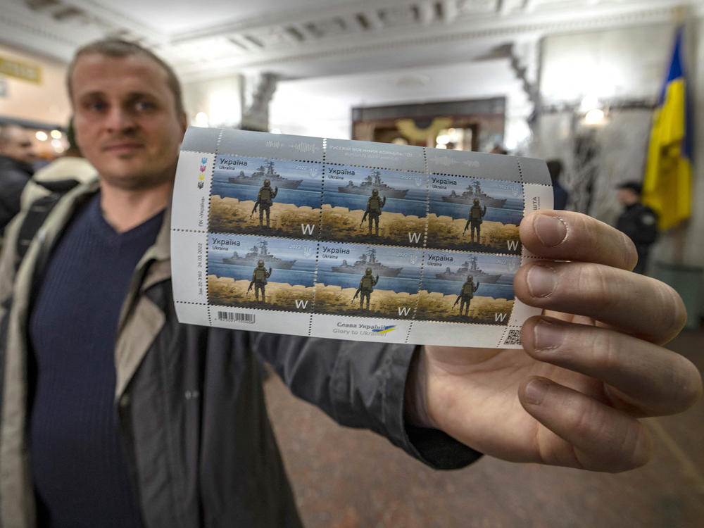 A Ukrainian man holds a set of stamps commemorating the Snake Island soldiers who responded to Russian troops' calls to surrender with a few choice words: 