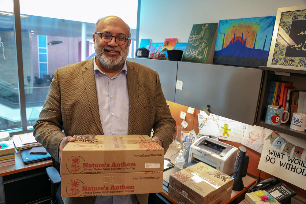 Omer Mozaffar, Loyola University Chicago's Muslim chaplain, holds boxes of dates in his office. Dates are typically eaten to break the fast during Ramadan.