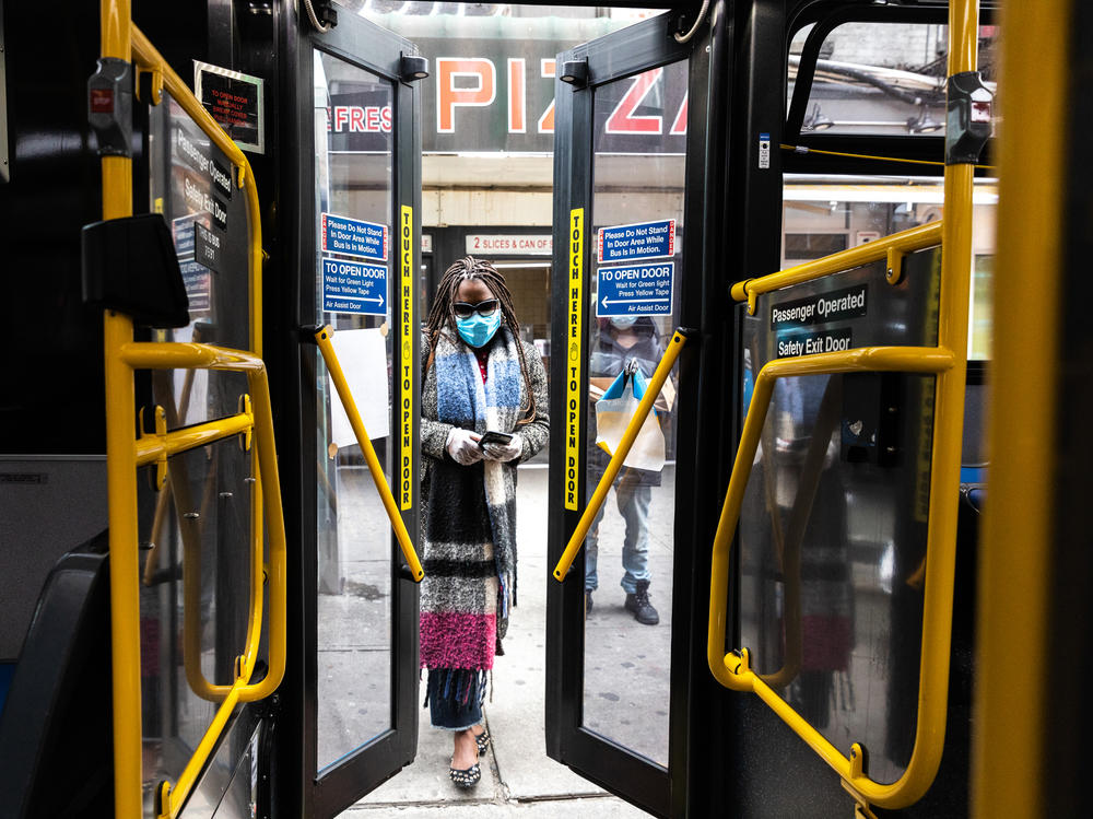 A woman wearing a protective mask enters a city bus on April 23, 2020 in New York City. New York's Metropolitan Transportation Authority approved a benefits program for workers who die of COVID-19-related causes.