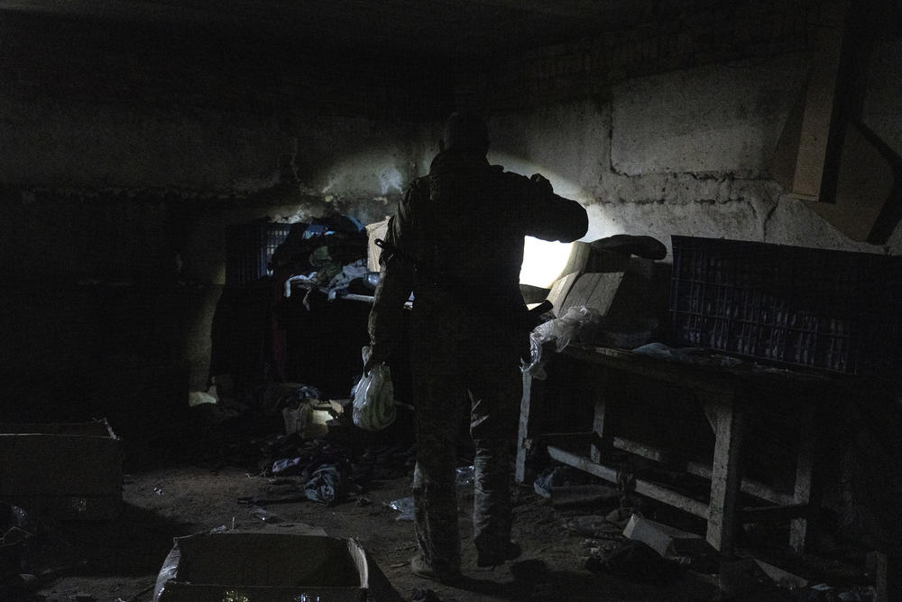 A Ukrainian military public affairs officer searches the basement of a warehouse previously used as a temporary barracks and field hospital by occupying Russian soldiers in Mala Rohan, Ukraine.