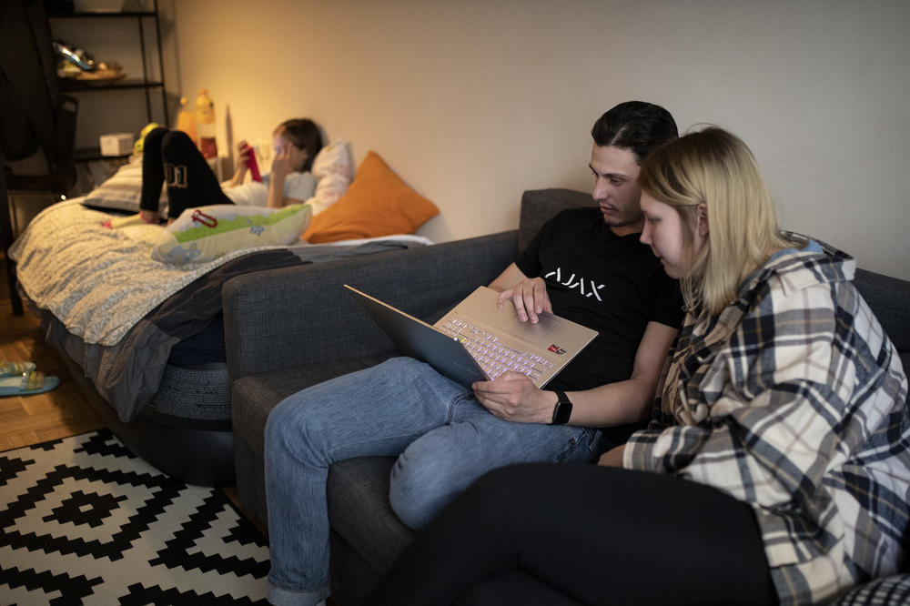 Josif Feny, center, uses his laptop next to Anet Pchelnikova, right, at their apartment in Sofia, Bulgaria, on Friday, April 22.