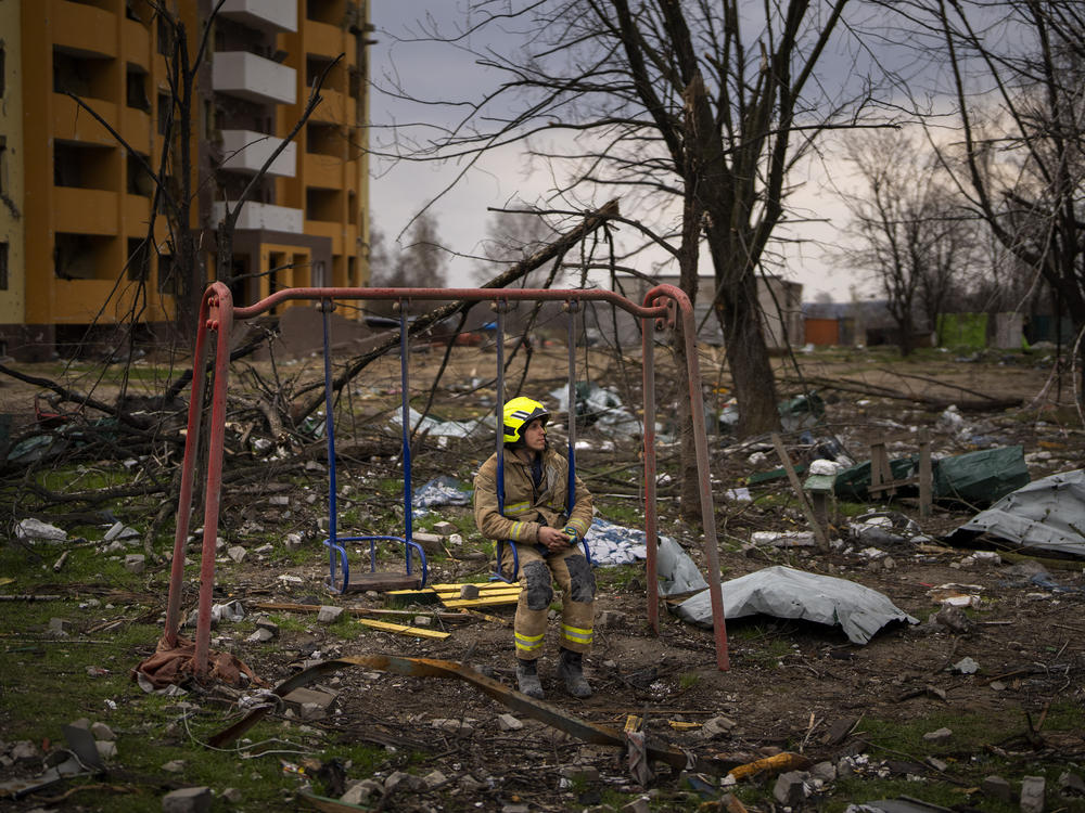 A firefighter sits on a swing next to a building destroyed by a Russian bomb in Chernihiv on Friday.