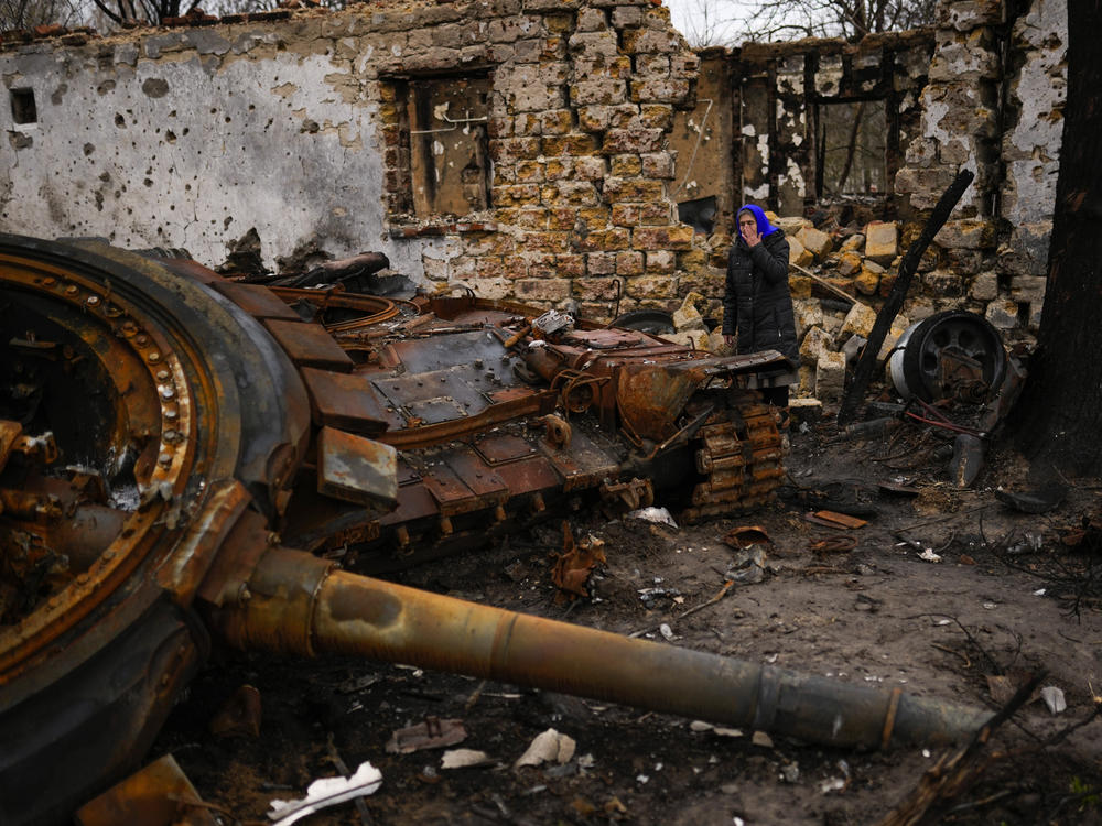Valentyna Sherba, 68, stands next to a Russian tank in the backyard of her father's home, both destroyed, in the aftermath of a battle between Russian and Ukrainian troops on the outskirts of Chernihiv, northern Ukraine, Saturday, April 23, 2022.