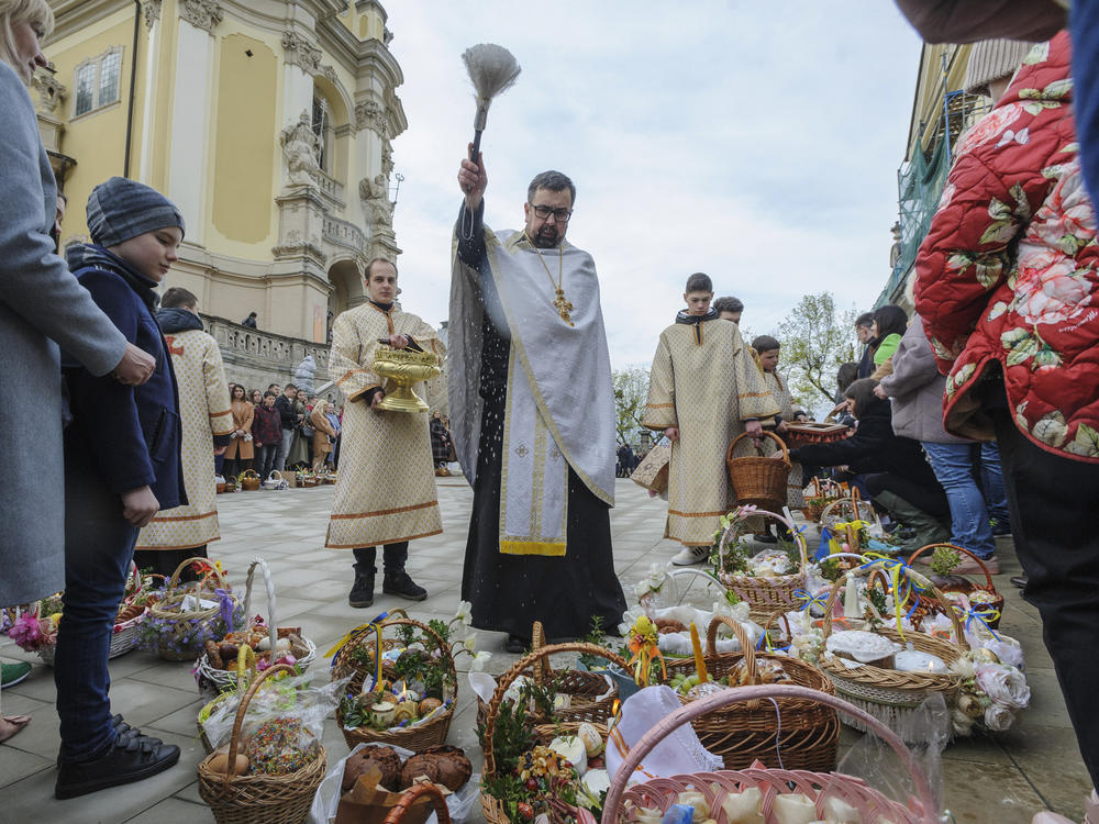 A Ukrainian priest blesses believers as they collect traditional cakes and painted eggs prepared for an Easter celebration in the in Lviv, Ukraine, Saturday, April 23, 2022.