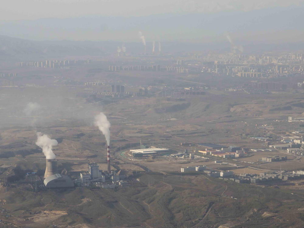 Smoke and steam rise from towers at the coal-fired Urumqi Thermal Power Plant as seen from a plane in Urumqi in western China's Xinjiang Uyghur Autonomous Region on April 21, 2021.