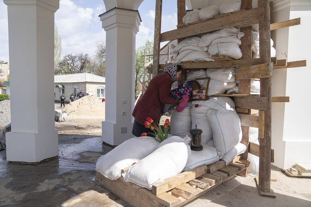<strong>April 24:</strong> An Orthodox believer helps her daughter to kiss a photo of a priest, founder of All Saints church during the Easter celebration in Bahmut, eastern Ukraine.