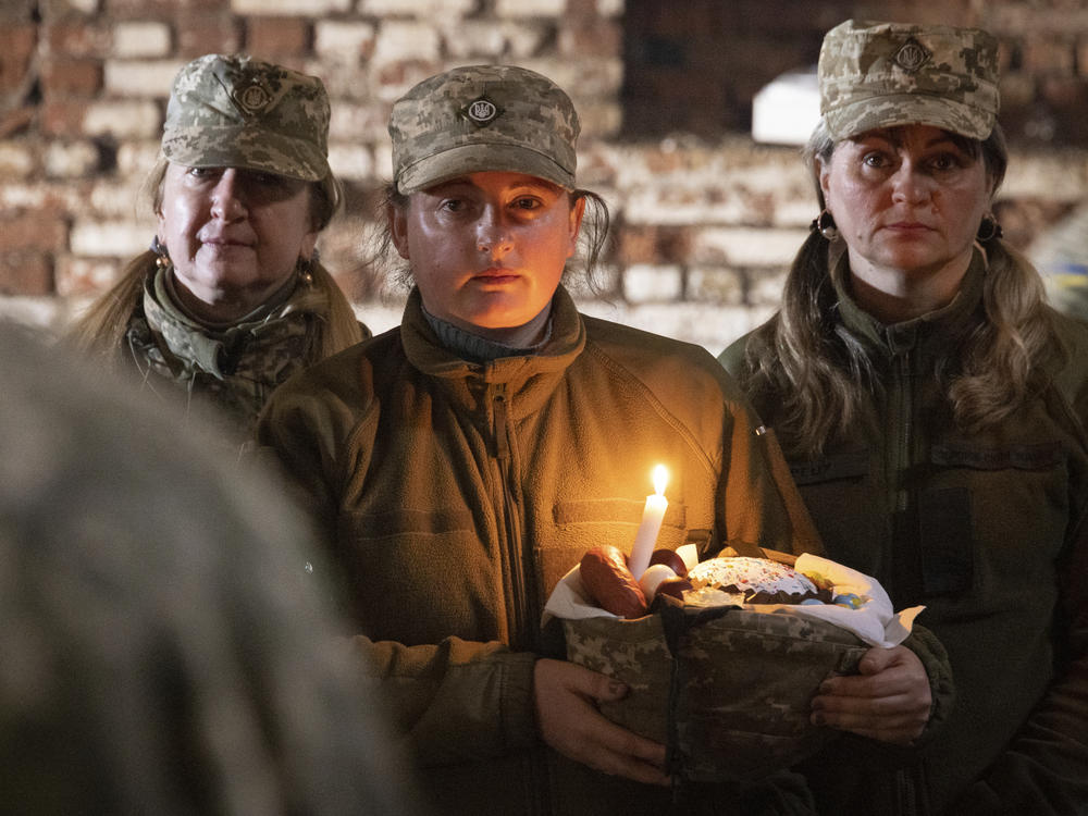Ukrainian servicewoman holding a basket with traditional cake and painted eggs attends an Orthodox service during the Easter celebration at the frontline position of 128 brigade of Ukrainian army near Zaporizhzhia, Ukraine, on Sunday, April 24, 2022.