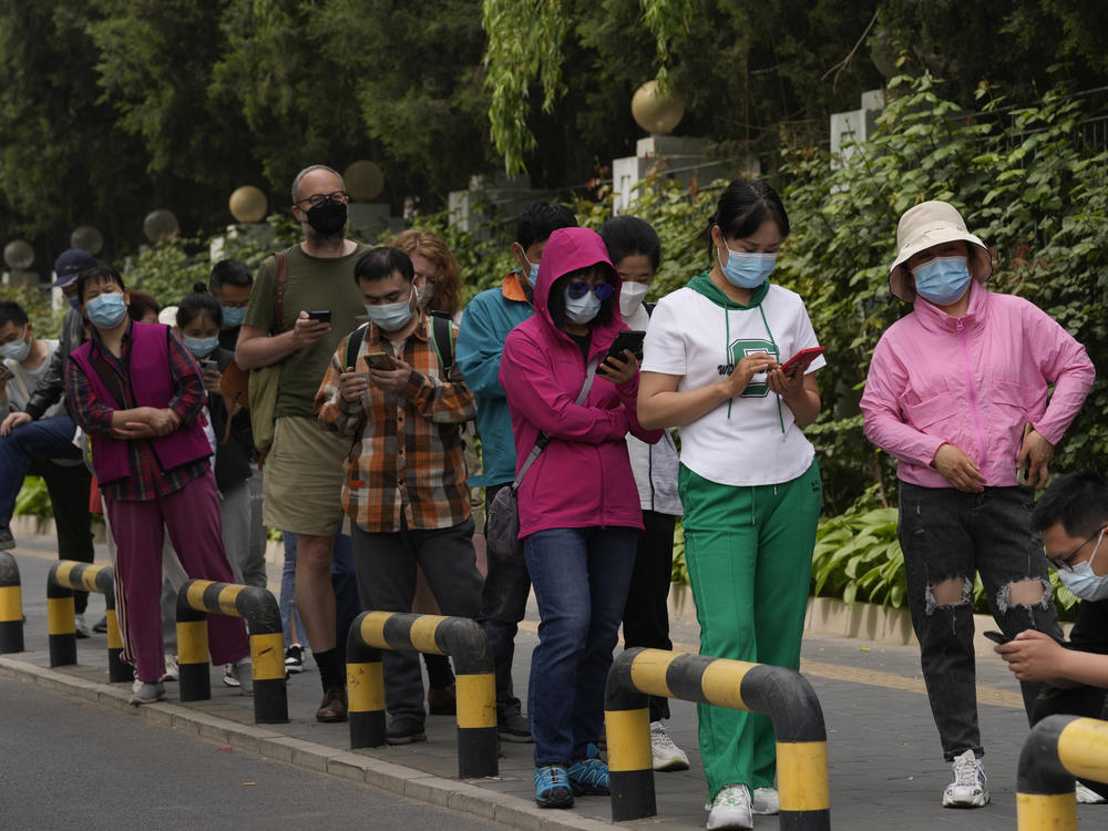 Residents wearing masks line up for mass COVID testing in Chaoyang District on Monday in Beijing.
