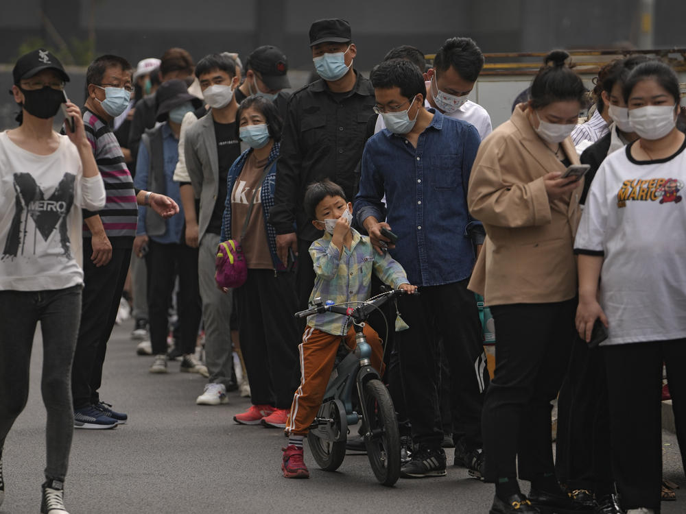Residents and office workers wearing face masks line up for mass coronavirus testing outside a commercial office complex in Chaoyang district on Monday in Beijing.