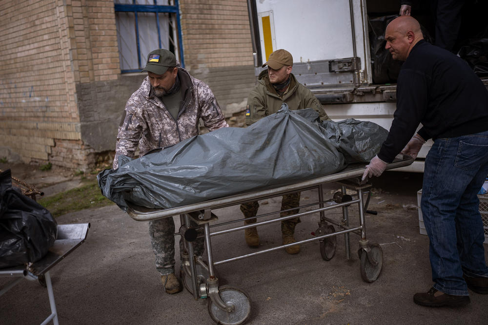 <strong>April 25:</strong> US Volunteers Wade Helton, left, and Darrell Loveless, center, work moving dead bodies from refrigerated trucks to the morgue in Bucha, on the outskirts of Kyiv.