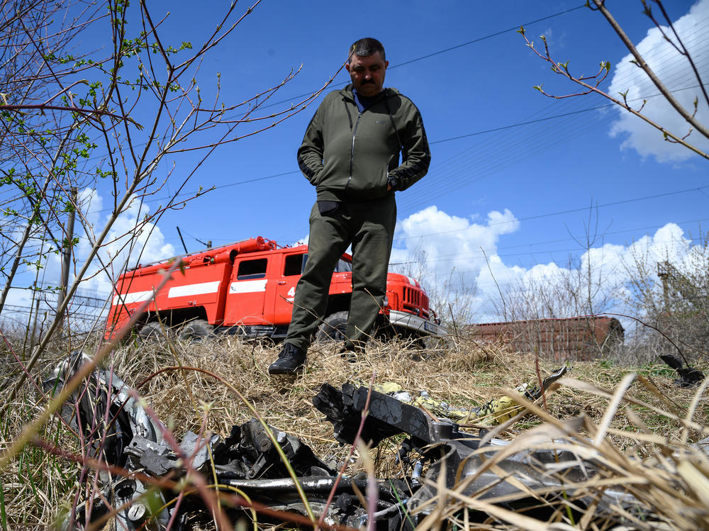 A resident looks at shards of twisted metal from a Russian rocket in undergrowth near a train line near Lviv, Ukraine, on Monday. The head of Ukrainian Railways said five rail facilities had been attacked by Russia Monday morning, including a substation supplying power to overhead lines, in Krasne, near Lviv.