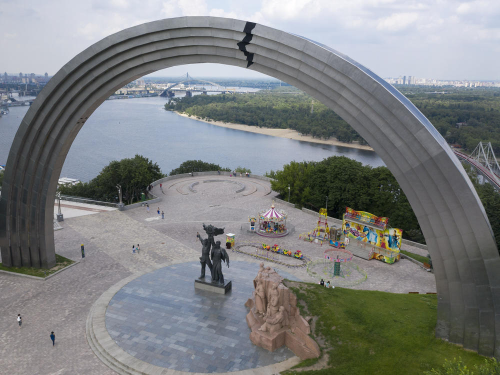 People walk in a city park around a Soviet-era monument in Kyiv, Ukraine, in June 2020.