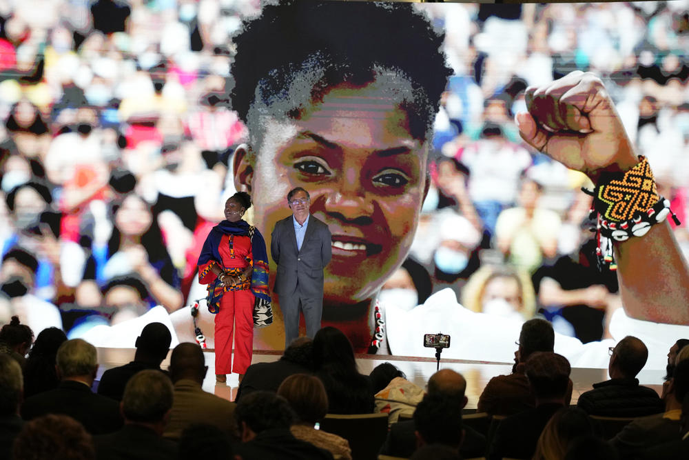 A large image of Francia Márquez is projected on a screen as she and presidential candidate Gustavo Petro stand on stage during a campaign event, March 23. Petro's running mate Márquez would be the first Afro-Colombian vice president if they win.