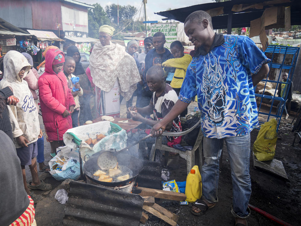 A man uses cooking oil to fry Mandazi, a type of fried bread, on a street in the low-income Kibera neighborhood of Nairobi, Kenya, Wednesday, April 20, 2022.
