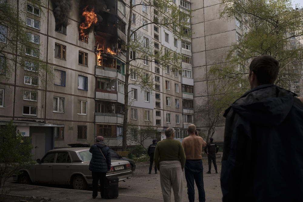 <strong>April 25:</strong> People watch as a residential building burns following a Russian bombardment in Kharkiv, Ukraine.