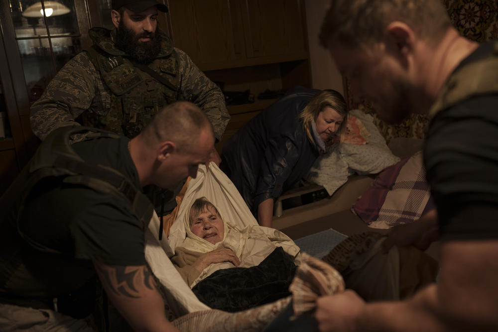 <strong>April 25:</strong> Volunteers evacuate an elderly woman out of her apartment in a frontline neighborhood as Russian bombardments continue in Kharkiv.