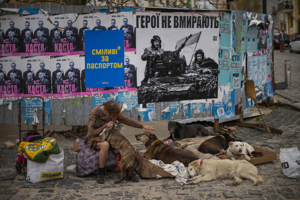 <strong>April 25:</strong> Iryna caresses dogs as she asks for money to support a center for abandoned dogs in Kyiv, Ukraine, next to a poster that reads, in Ukrainian: 