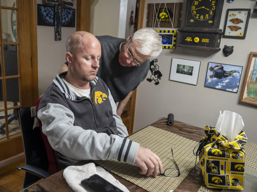 Don Miller assists his son, Jon, into the kitchen. Jon's stroke and cancer treatment, which included chemotherapy, radiation and two stem cell transplants, left him brain severely damaged.