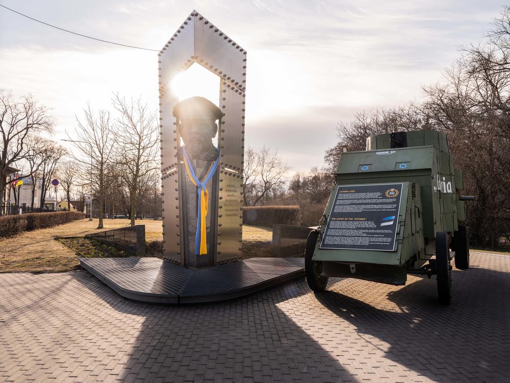 A scarf with the Ukrainian flag colors is draped over a war hero statue next to the first Estonian armourd car in Tallin, Estonia.