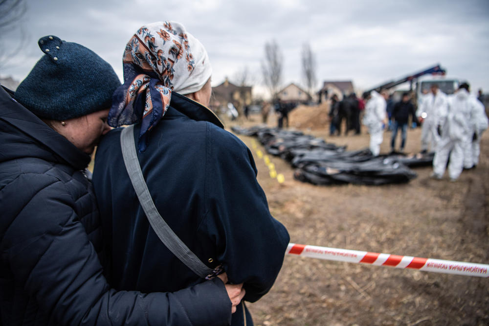 Women embrace each other as bodies are exhumed from a mass grave to be inspected for possible war crimes on April 8 in Bucha, outside Kyiv, Ukraine.