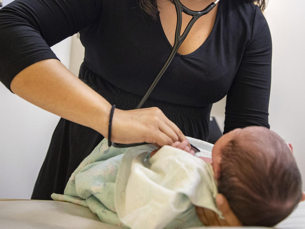 A pediatrician examines a newborn baby in her clinic in Chicago on Tuesday in 2019. In a new policy statement released Monday, the American Academy of Pediatrics says it is putting all its guidance under the microscope to eliminate 