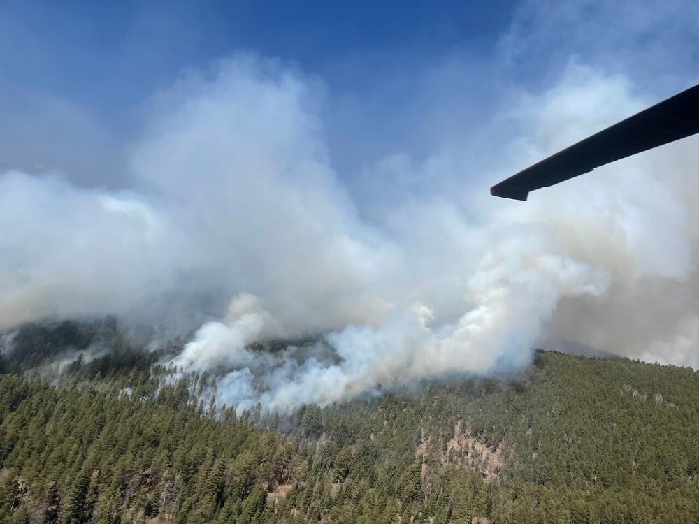 A New Mexico National Guard Aviation UH-60 Black Hawk flies as part of firefighting efforts, dropping thousands of gallons of water from the air on the Calf Canyon/Hermits Peak fire in northern New Mexico on Sunday.