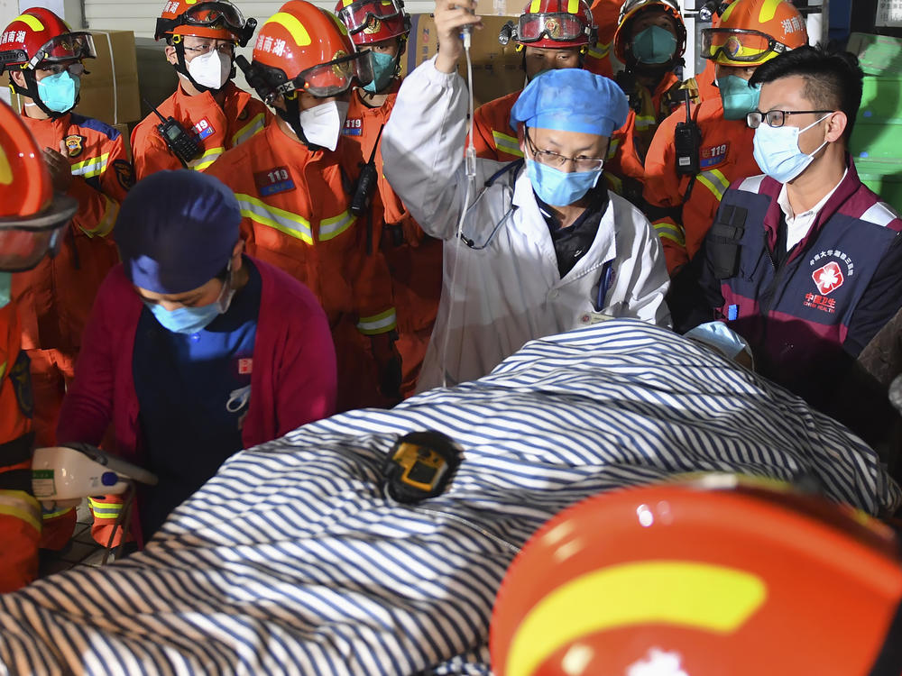 In this photo released by Xinhua News Agency, rescuers transfer a ninth person pulled from the rubble 88 hours after a self-built residential building collapsed in Changsha, central China's Hunan Province, May 3, 2022.