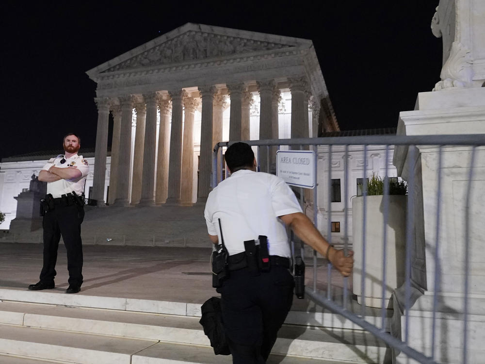 Police move barricades in place as a crowd of people gather outside the Supreme Court, Monday night, May 2, 2022 in Washington.