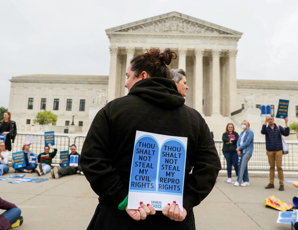 A protester stands in front of the U.S. Supreme Court building Tuesday holding a sign that reads, 