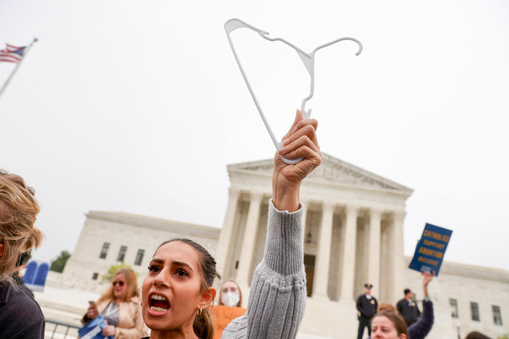 A protester holds a coat hanger aloft outside the U.S. Supreme Court building Tuesday.