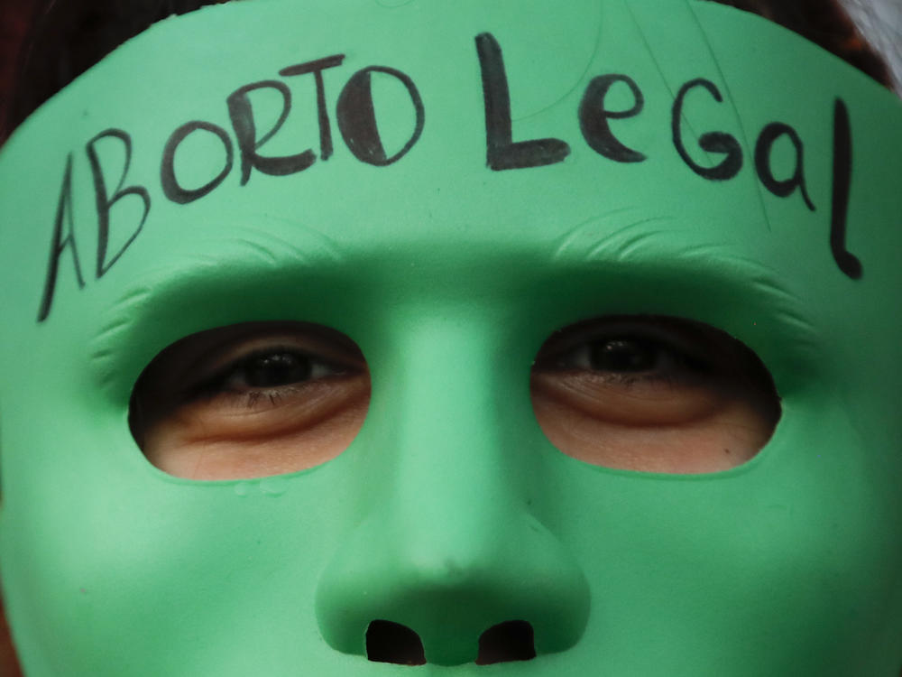 An abortion-rights activist wears a mask with text that reads in Spanish 