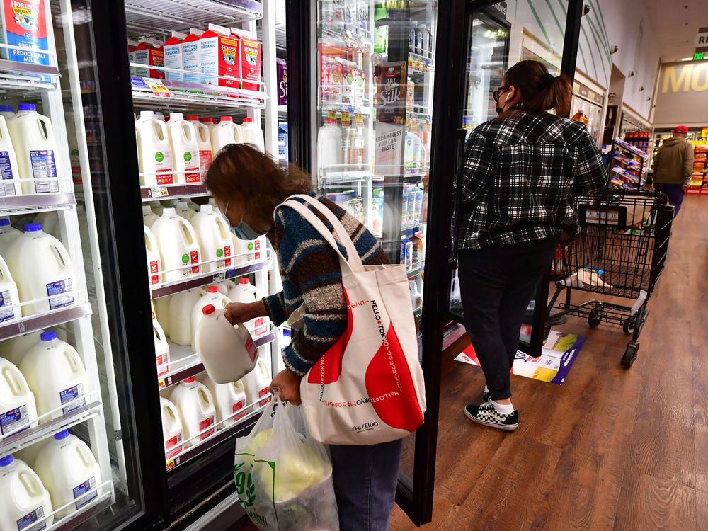 A person pulls out a gallon of milk as people shop at a grocery store in Monterey Park, Calif, on April 12. Prices for groceries and other consumer goods have continued to surge.