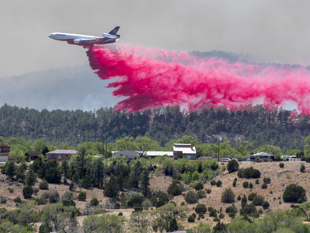 A slurry bomber dumps the fire retardant between the Calf Canyon/Hermit Peak Fire and homes on the westside of Las Vegas, N.M., Tuesday, May 3, 2022.